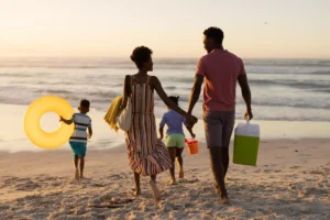 Família chegando na praia com 10 dicas para a sua viagem de verão ser incrível! Clube Viajar Faz Bem SBTUR